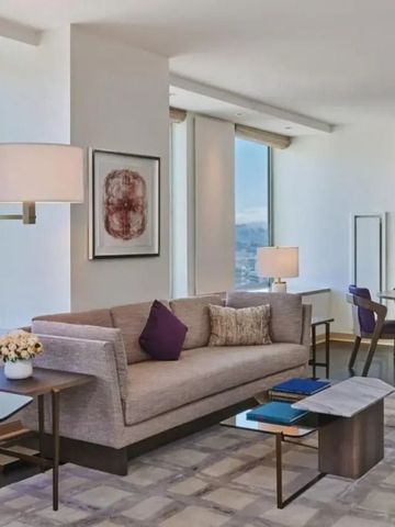 Heller Wohnbereich mit großem Sofa, Aussicht auf die Stadt und moderner Einrichtung.