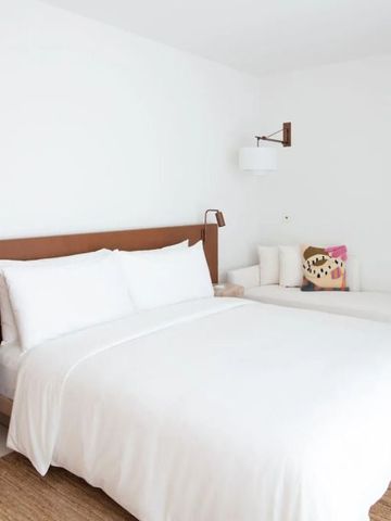 Helles Hotelzimmer mit großem Bett weißen Kissen und minimalistischer Einrichtung