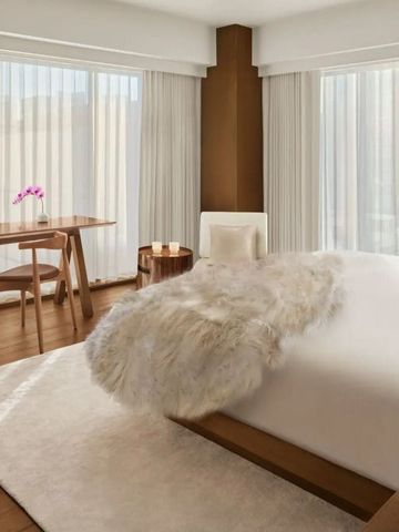 Helles Hotelzimmer mit modernem Holzschreibtisch und flauschiger Tagesdecke