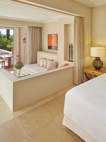Helles Hotelzimmer mit direktem Zugang zu einer Terrasse mit Pool, komfortable Sitzgelegenheiten.