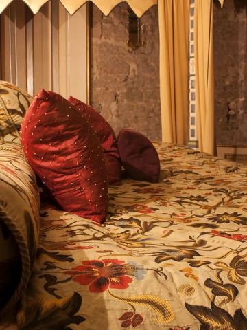 Prunkvolles Bett mit reich dekorierten Textilien in einem opulenten Raum.