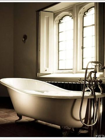 Freistehende Badewanne vor einem großen Bogenfenster