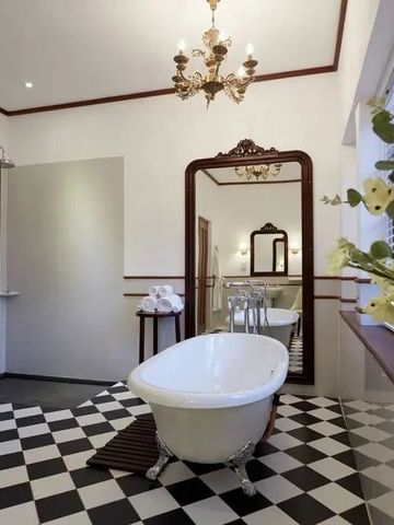 Badezimmer mit dekorativer Badewanne und großem Wandspiegel