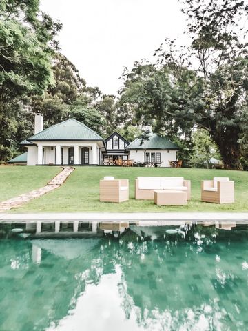 Luxusvilla mit Grünflächen und Pool in bewaldeter Umgebung.