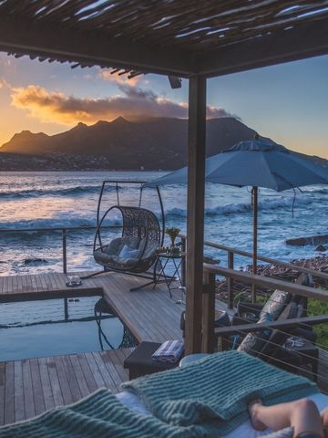 Privater Pool mit Meerblick in der Abenddämmerung, Hängesessel auf der Terrasse.
