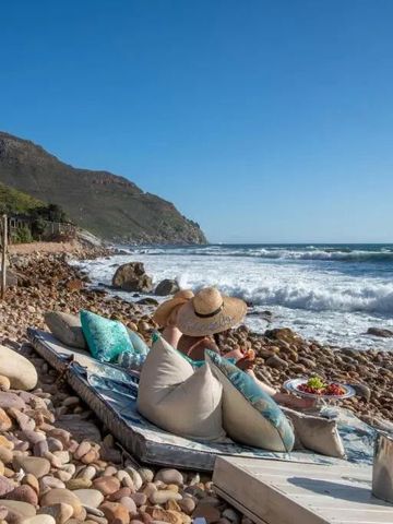 Frau am Strand auf einer gepolsterten Liege mit Blick auf das Meer.