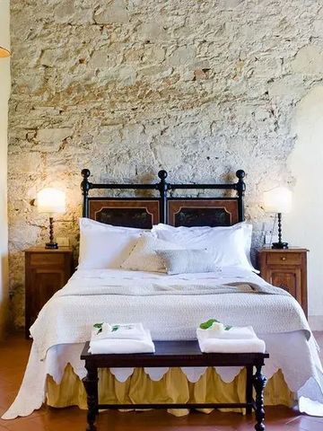 Schlafzimmer im Landhausstil mit Steinwand und Doppelbett im Hotel Torre a Cona