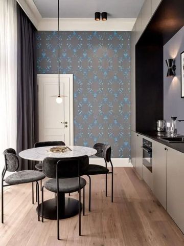 Modernes Hotelzimmer mit kleiner Küche, Esstisch und stilvoller Wandtapete