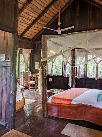 Luxuriöses Zimmer mit Holzelementen, Himmelbett und farbenfrohen Kissen