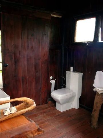 Rustikales Badezimmer aus Holz mit Toilette und Waschbecken