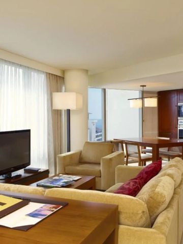 Geräumiges Wohnzimmer in einer Suite mit modernen Möbeln und großem Fenster.