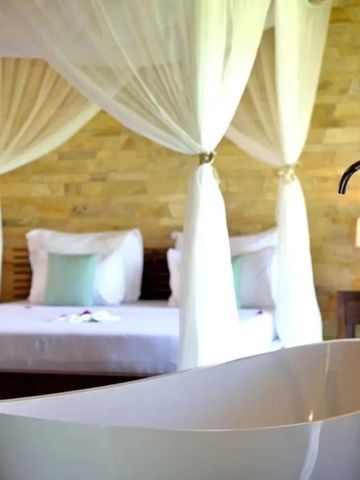 Elegantes Badezimmer mit freistehender Wanne und Blick auf Himmelbett
