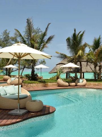 Poollandschaft mit Sonnenliegen und Palmen am Strand