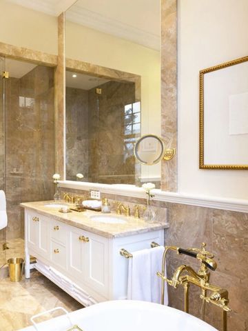 Marmorbad mit goldenen Armaturen und großer Dusche