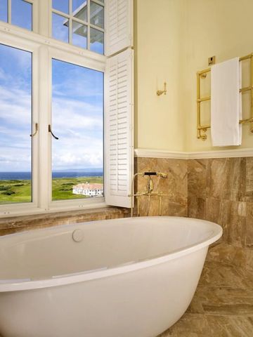 Freistehende Badewanne mit Fensterblick auf Küstenlandschaft