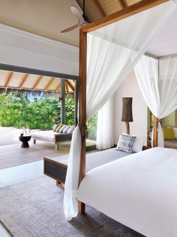 Helles Schlafzimmer mit Himmelbett und Blick auf eine tropische Terrasse