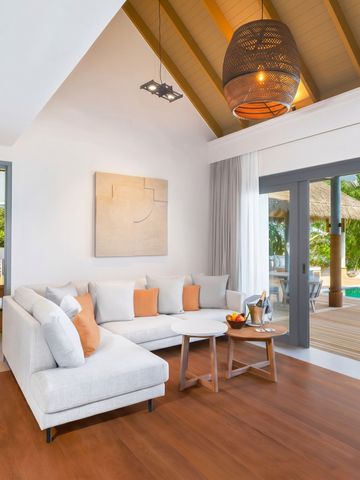 Elegantes Wohnzimmer mit Sicht auf Terrasse und Pool in maledivischer Villa.