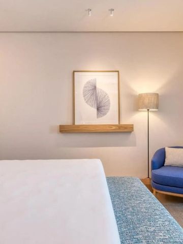 Helles Schlafzimmer mit minimalistischem Kunstwerk und gemütlicher Sitzecke