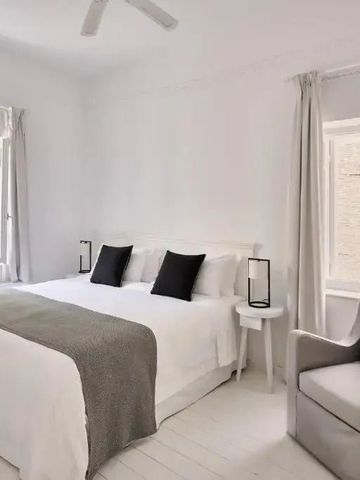 Elegantes Zimmer mit Doppelbett in Weiß- und Grautönen mit stilvollen Details