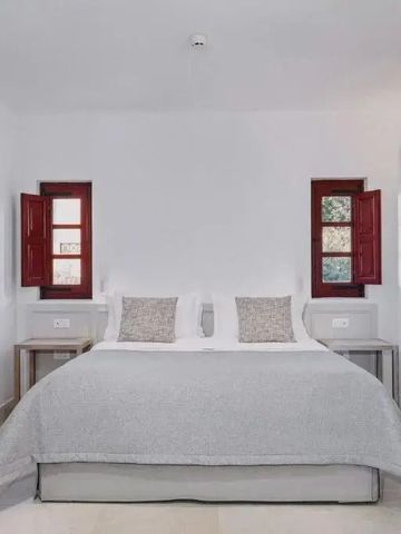 Modernes Schlafzimmer mit Doppelbett zwischen roten Fensterläden im Landhausstil