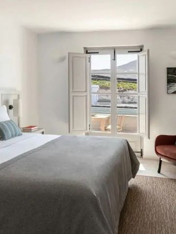 Helles Zimmer mit Doppelbett und Fensterblick auf Terrasse und Landschaft