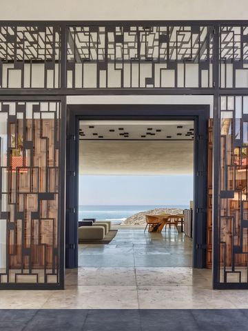 Modern gestalteter Eingang mit geometrischen Metallmustern und Blick aufs Meer