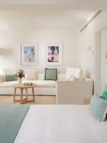 Luxuriöses Schlafzimmer mit angrenzender Sitzecke und pastellfarbenem Dekor.