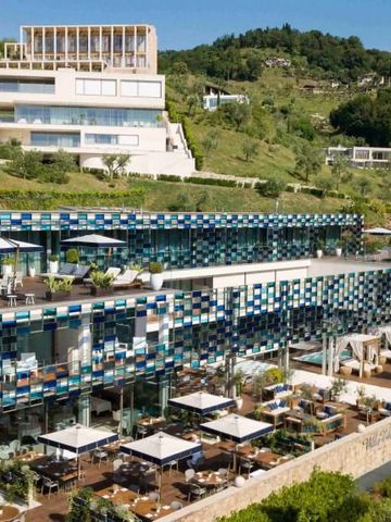 Spektakuläre Ansicht eines innovativen, gläsernen Hotelgebäudes eingebettet in hügelige Landschaft