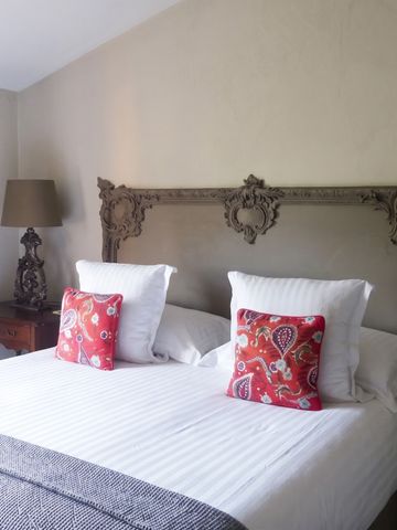 Blick auf ein elegantes Schlafzimmer mit verzierten Kopfteil und roten Kissen