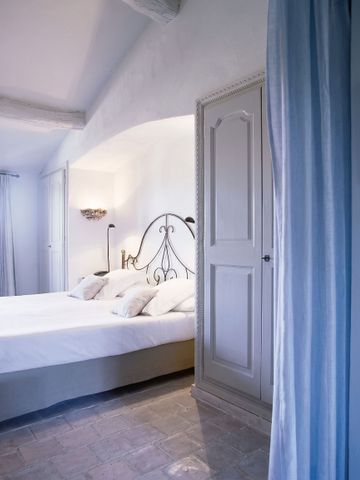 Helles Schlafzimmer mit elegantem Eisenbett und blauen Vorhängen