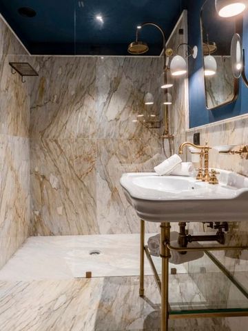 Luxuriöses Badezimmer mit Marmorwänden und goldenen Armaturen