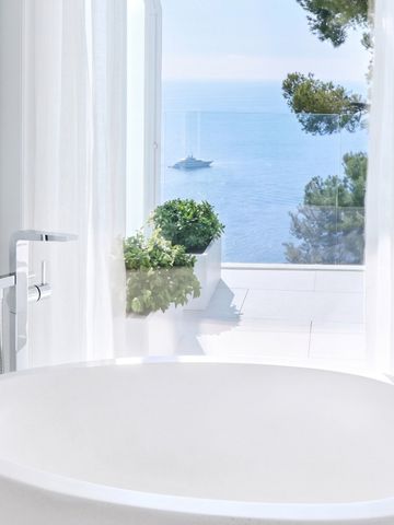 Weißes Bad mit freistehender Wanne und Panoramablick aufs Meer