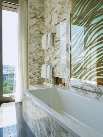 Geräumiges Badezimmer mit großer Badewanne und Marmordetails im Waldorf Astoria Berlin.
