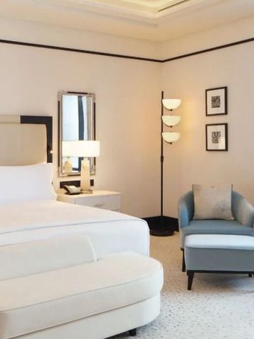 Elegantes Hotelzimmer mit großem Bett und bequemer Sitzgelegenheit im Waldorf Astoria Doha