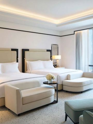 Helles Zimmer mit zwei komfortablen Doppelbetten und Sitzbereich im Waldorf Astoria Doha