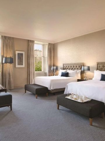 Elegantes Hotelzimmer mit zwei großen Betten und Blick auf Edinburgh