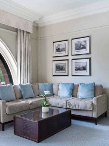 Gemütliches Wohnzimmer mit Ecksofa und großen Fenstern im Caledonian Edinburgh Hotel