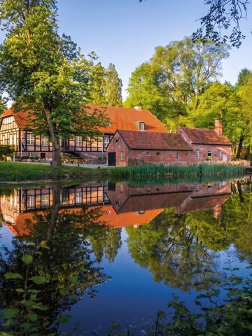 Historisches Gebäude an einem ruhigen Teich im Grünen