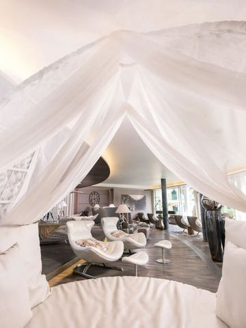 Lounge mit weißen Sesseln und eleganten Stoffen unter einem Baldachin