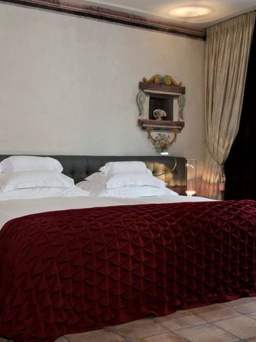 Elegantes Schlafzimmer mit rotem Überwurf und klassischer Wanddekoration im Widder Hotel