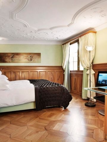 Luxuriöses Zimmer mit Holzvertäfelung, stilvollen Möbeln und Stuckdecke im Widder Hotel
