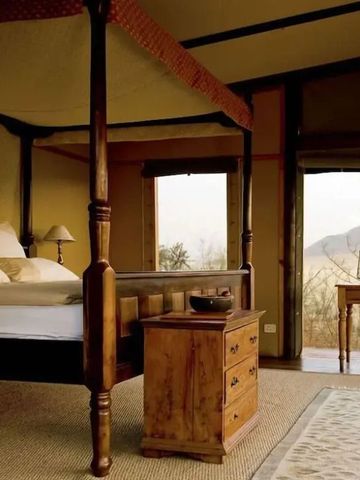 Rustikales Schlafzimmer mit Himmelbett und Panoramablick im wolwedans Boulders Camp.