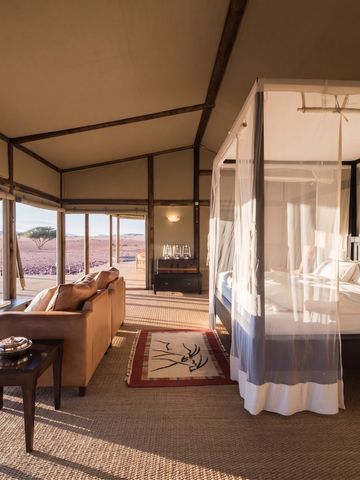 Großzügiges Zimmer mit Himmelbett und Panoramafenstern im Wolwedans Boulders Camp.