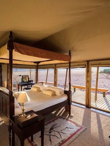 Komfortables Schlafzimmer mit Himmelbett und Wüstenblick im Wolwedans Boulders Camp.