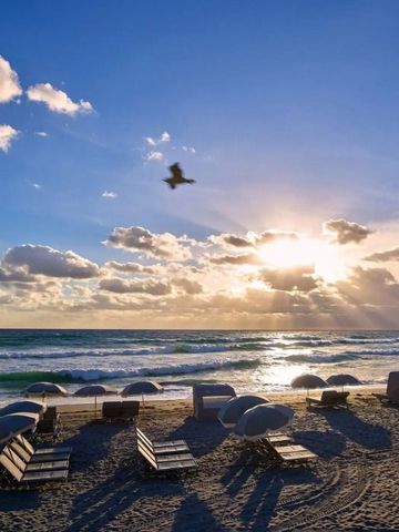 Sonnenaufgang über dem Meer mit Strandliegen und Sonnenschirmen