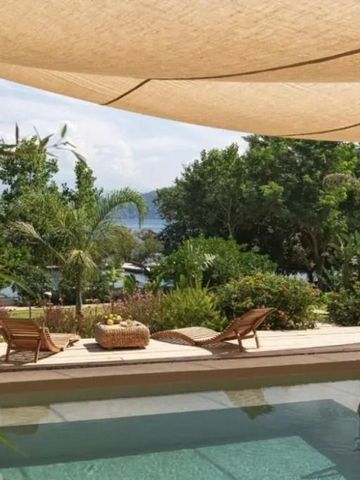 Pool mit Liegestühlen und Blick auf das Meer und üppige Vegetation