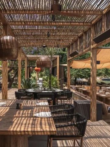 Restaurant mit Holzdekor und Outdoor-Sitzbereich unter Schattensegeln