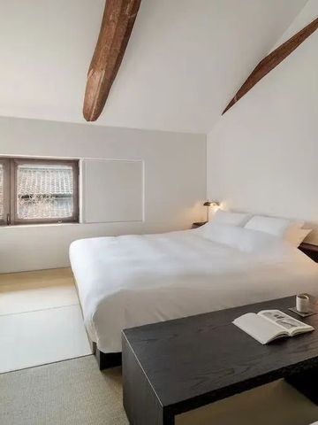 Geräumiges Hotelzimmer mit Dachbalken, großem Bett und Arbeitsbereich
