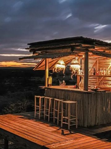 Kleine Outdoor-Bar aus Holz im Abendlicht mit Sitzgelegenheiten.