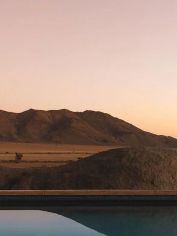 Infinity-Pool mit Blick auf Wüstenlandschaft bei Dämmerung